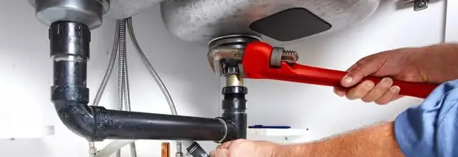 Garbage disposal repair technician tightening the sink drain and disposal connection in Columbia, SC