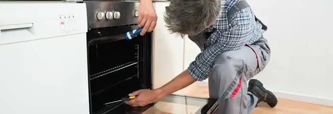 Oven repair technician inspecting and servicing an electric oven in Columbia, SC