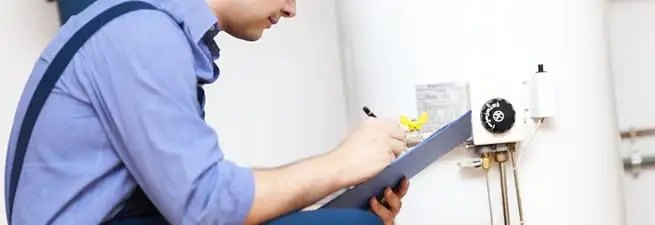 Water heater repair technician inspecting the unit and recording service notes in Columbia, SC