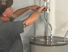 Water heater repair technician tightening supply line connections in Columbia, SC